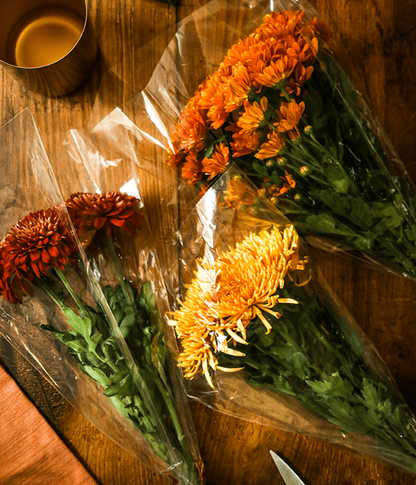 Three wrapped fall-colored bouquets of Heinen's Flowers