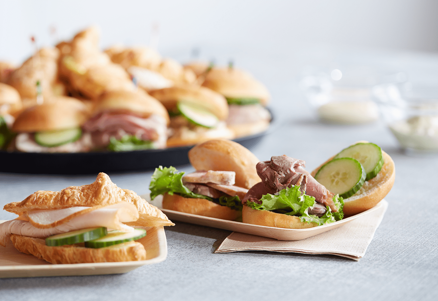 An Assortment of Mini Meat, Vegetable and Cheese Sandwiches on Croissants and Fresh Bread