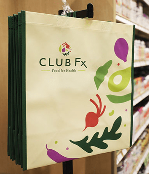 A Club Fx tote bag hanging in an aisle at Heinen's