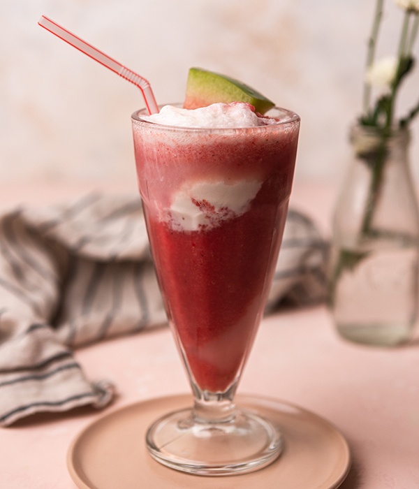 Watermelon float garnished with a watermelon slice in a milkshake glass with a straw