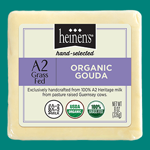 A Packaged Block of Heinen's Organic A@2Grass Fed Gouda Cheese on a Green Background