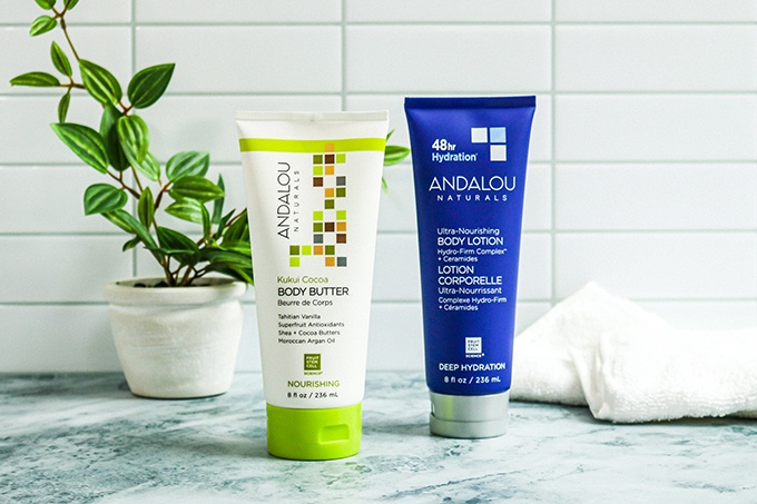 Skincare from Andalou, a natural skincare brand, on a marble countertop; From left to right: Kukui Body Butter and Deep Hydration Lotion 