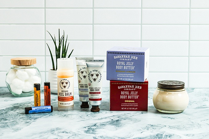 Skincare from Savannah Bee Company on a marble countertop; From left to right: Lip Balms, Heel Balm, Hand Creams, Royal Jelly Body Butters