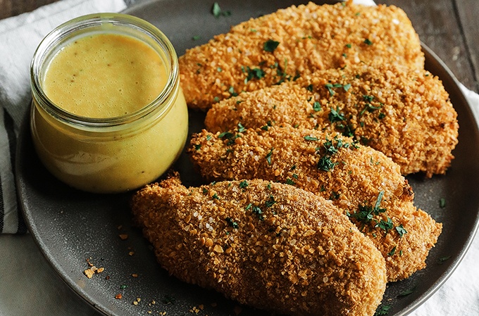 Corn flake crusted chicken served on a plate with a side of homemade honey mustard sauce