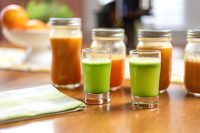 Assortment of Juices and Juice Shots on wooden table in Glasses and Mason Jars
