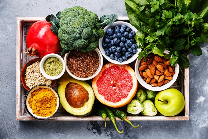 Overhead view of an assortment of fruits, veggies, leafy greens, whole intact grains, nuts and seeds