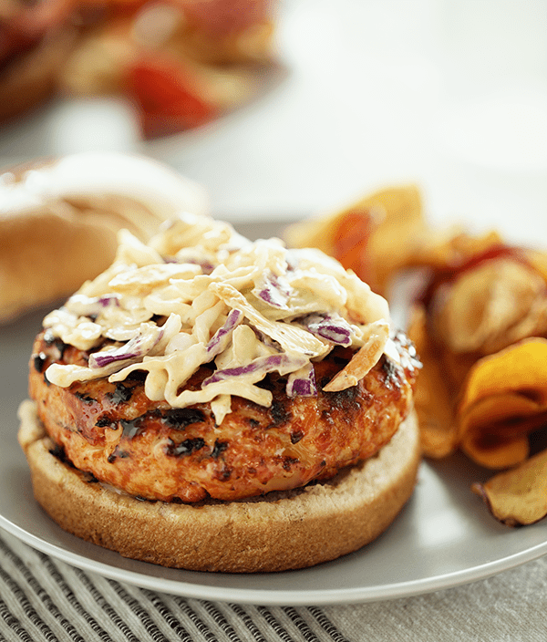 Salmon Burger with Chipotle Slaw served on a plate with chips