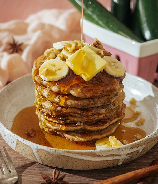 Zucchini Bread Pancakes on a Plate being drizzled with Heinen's Maple Syrup