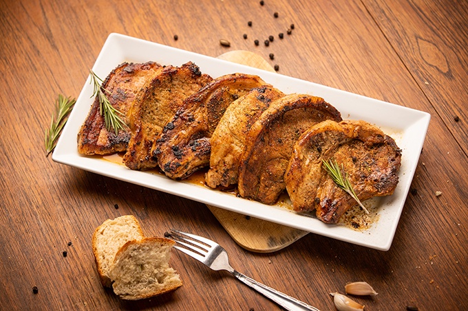 Grilled pork cutlet with spices and bread on wooden background