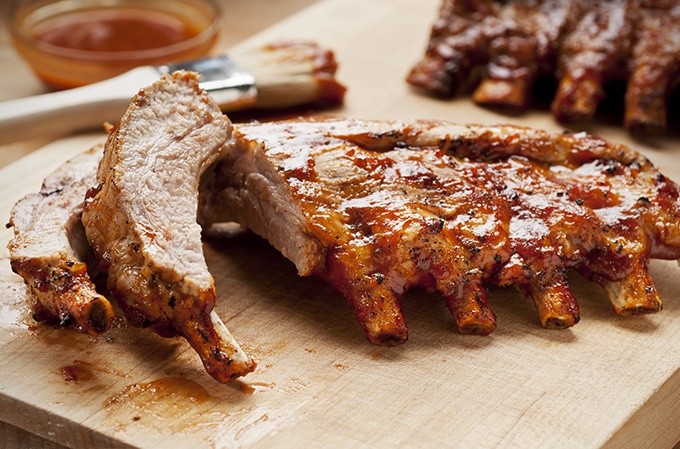Barbecue pork ribs with sauce on a cutting board.