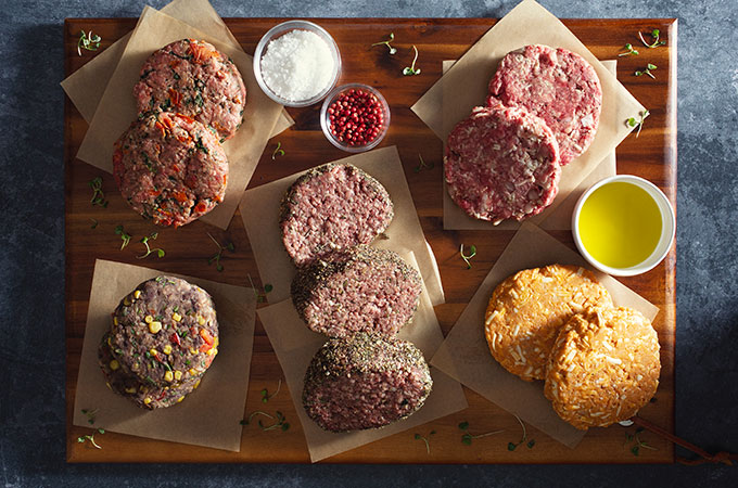 Heinen's Raw Gourmet Burgers on a Cutting Board with Butcher Paper with Seasonings and Sauces
