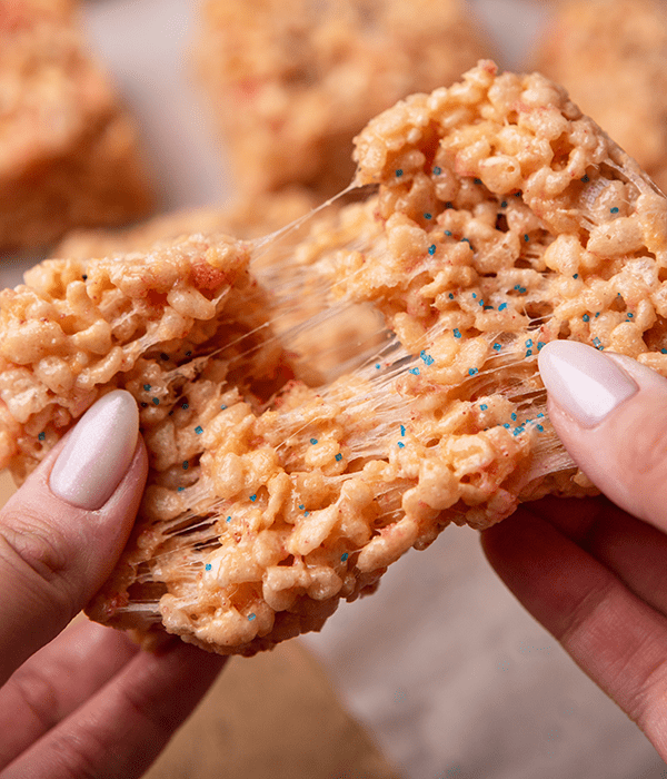 Two Hands Pulling apart a Strawberry Crunch Rice Crispie Treat