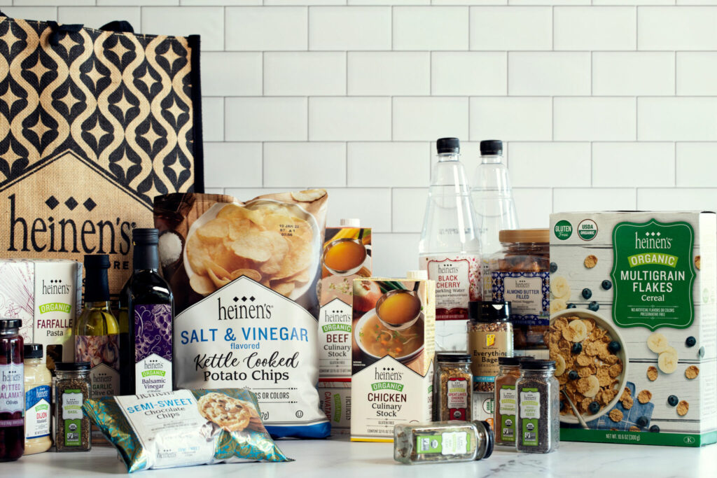 Pantry Essentials with the Heinen's Brand label including potato chips, seasonings, chicken stock, cereal, and oils.