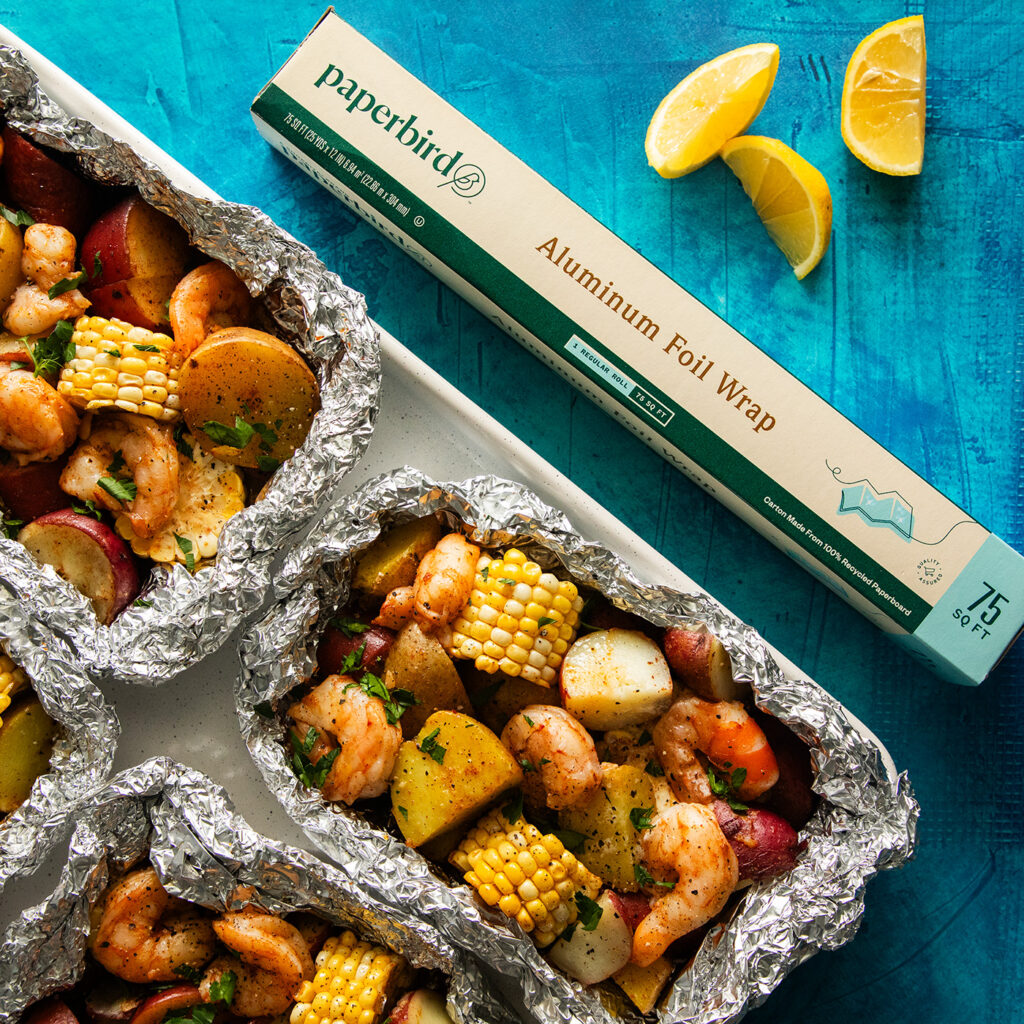 A Roll of Paperbird Aluminum Foil Beside a Tray of Shrimp and Vegetable Foil Packets