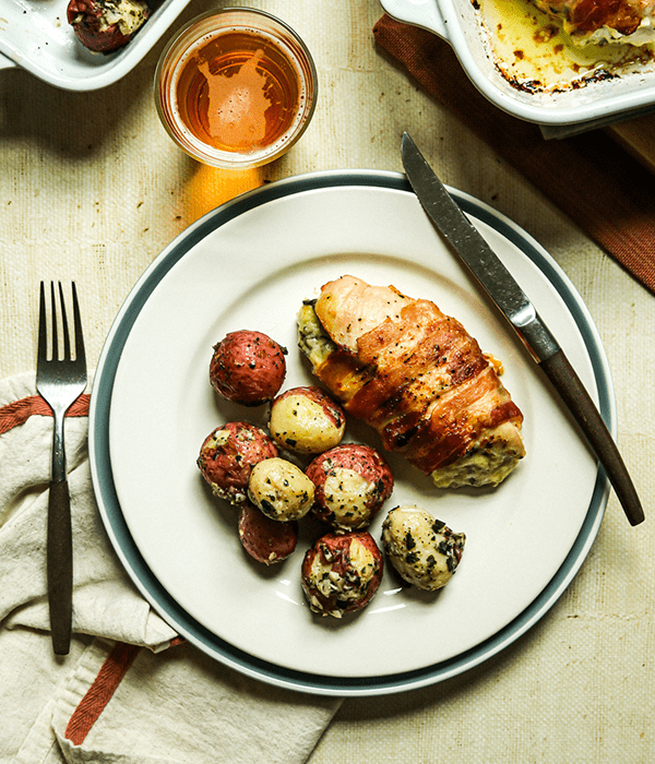 Heinen's Adams Reserve Stuffed Chicken Breast and Heinen's Garlic and Herb Roasted Potatoes on a Plate with a Fork and Knife