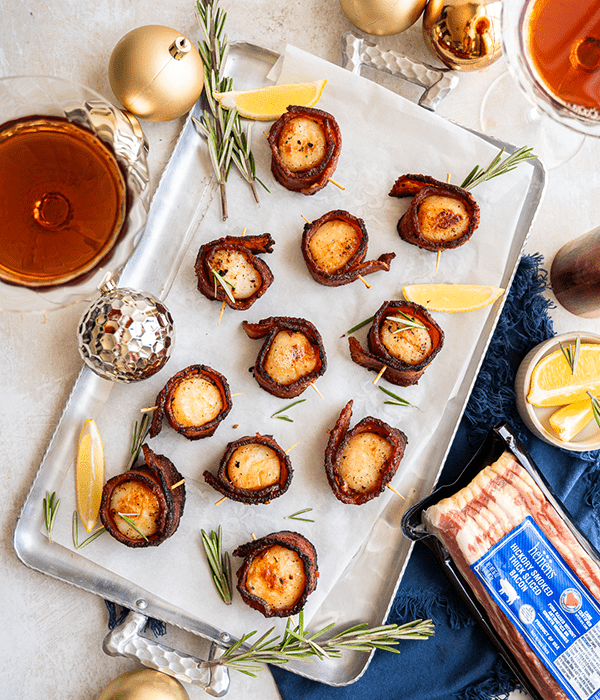 A Portrait Style Image Bacon Wrapped Scallops on a Parchment-Lined Baking Tray