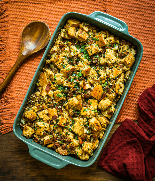 Herb Stuffing with Bacon and Sausage in a Casserole Dish with a Wooden Serving Spoon