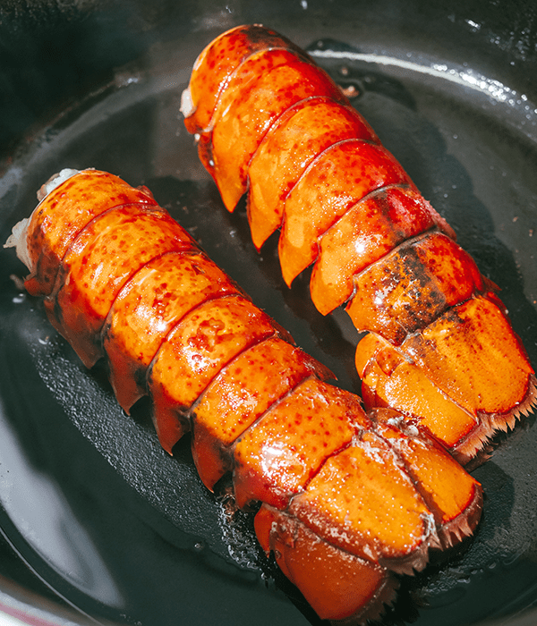 Two Cooked Lobster Tails in a Skillet