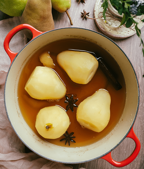 Four Peeled Pears in a Pot with An Apple Cider Poaching Liquid and Spices