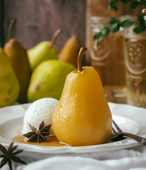 One Poached Pear on a Dessert Plate with a Scoop of Vanilla Ice Cream and Star Anise