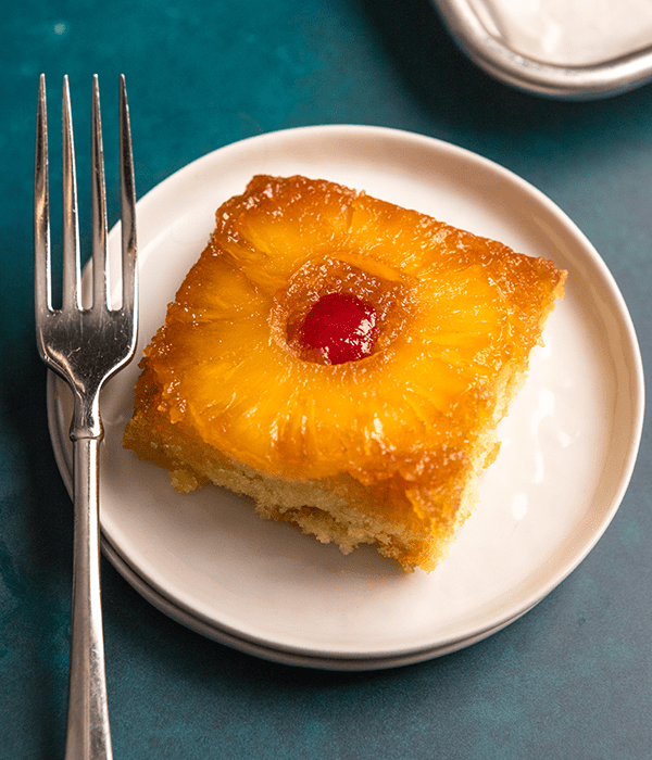 A Slice of Pineapple Upside Down Cake on a Plate with a Fork