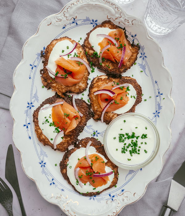 A Top-Down Image of a Serving Plate of Smoked Salmon Potato Pancakes with a Small Bowl of Creme Friache.