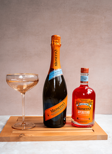 A Bottle of Mionetto Alcohol Removed Sparkling Wine Beside a Bottle of Mionetto Apertivo and a Coupe Glass